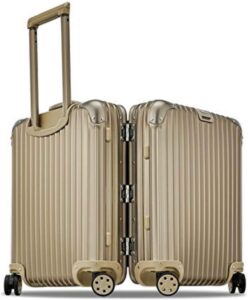 A gold suitcase with wheels on a white background.